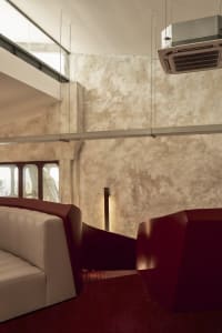 Modern interior design featuring textured stucco walls and a red geometric cube.