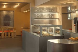 Modern bakery with metal and glass counter displaying baked goods.