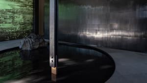 A modern spa interior featuring dark metal tiles, concrete elements, and natural rocks.
