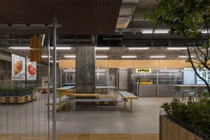 Industrial-style food court with concrete and metal surfaces, and open seating areas.