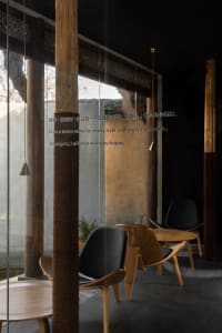 Modern restaurant interior with wooden furniture, black chairs, and glass walls