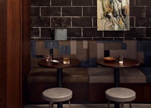 Industrial-themed cafe with dark walls, leather benches, and round tables.