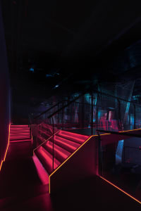 A modern nightclub staircase illuminated with metal lights at night.