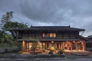 A modern house with a zinc roof and wooden terrace in a residential setting.