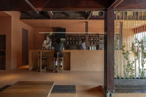 A rustic coffee shop interior with wooden materials, shelves filled with coffee-related items, and a barista working behind a