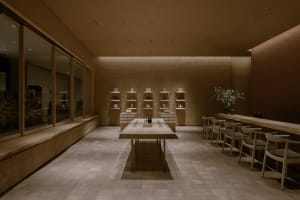 A minimalist restaurant interior featuring wooden furniture and shelves.