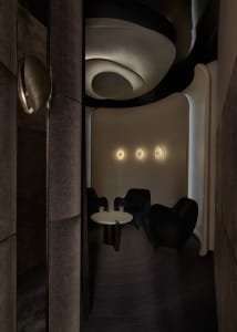 A modern bar with concrete walls and a circular table with two glasses of water.