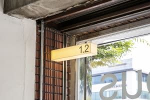 A modern street sign with a metal frame and illuminated numbers indicating the floor number.