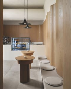 A minimalist cafe interior with wooden tables and concrete flooring.