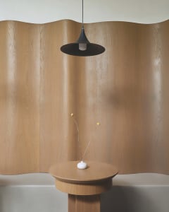 A sleek, modern side table made of wood with a minimalist design, featuring a white object with two yellow elements.