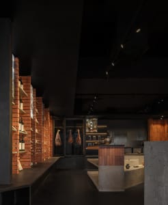 A modern industrial restaurant bar featuring exposed brick walls, concrete surfaces, and a mix of contemporary and rustic ele
