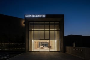 A modern coffee shop facade with large glass windows and a lit sign.
