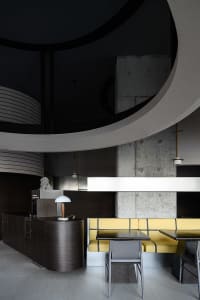 A modern restaurant interior featuring dark wood accents and concrete walls.