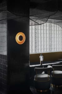 A minimalist bar counter with black glass tiles and a modern light fixture