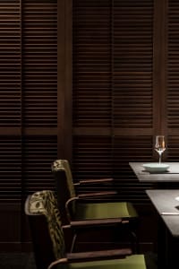 A minimalist restaurant interior featuring wooden decor and green furniture.