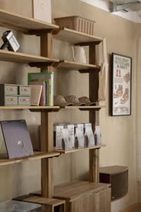 Minimalist interior design featuring wooden shelves with books, bags, and other products displayed.