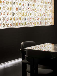 A modern restaurant setting with a glass window featuring intricate patterns and colorful illustrations.