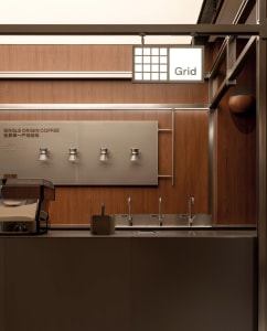 A modern, industrial-style coffee shop kitchen with stainless steel fixtures and a minimalist design.