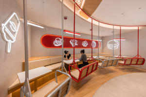 People sitting at a modern cafe with metal chairs and neon signs.