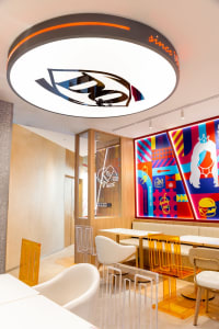 A modern restaurant interior with colorful walls, round light fixture, and contemporary seating.