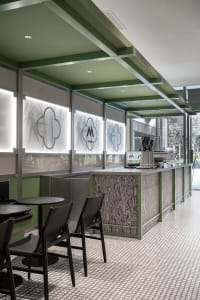A modern cafe interior featuring metal, glass, and walnut materials.