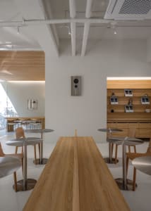 A minimalist coffee shop interior with wooden tables and stools.