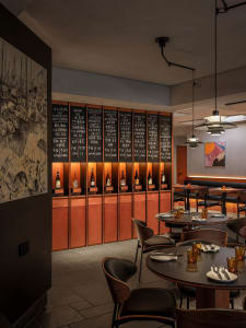 A modern restaurant dining room featuring wooden tables, glass walls, and metal chairs.