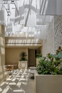 A modern-style coffee shop interior with concrete elements and hanging fabric screens.