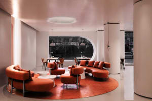 Modern coffee shop featuring orange leather seating and round tables.