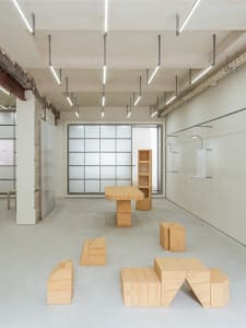 Minimalist installation art featuring geometric wooden structures in a modern, industrial-style room