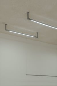 A modern interior space featuring concrete walls and minimalist lighting fixtures.