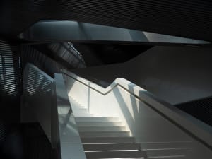 Modern, minimalist concrete staircase with metallic handrails in a contemporary architectural setting.