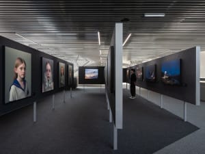 An industrial exhibition with black walls and various artworks displayed on the walls.