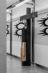 Modern minimalist interior design featuring a black-framed glass entryway with an abstract logo design.