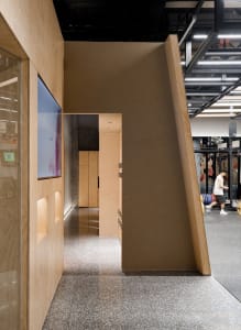 Industrial-style office space with a doorway, brownboard, and a mix of materials like wood, glass, and concrete.