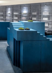 A retail space with blue wooden structures and green foliage displays.