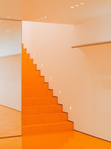 A minimalist staircase with orange tiles and white walls.