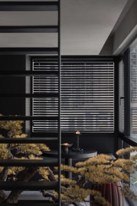 Modern living room featuring matte black metal window blinds and wooden furniture.