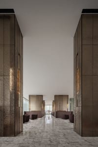 A modern hotel lobby featuring metallic-textured walls and marble floors.