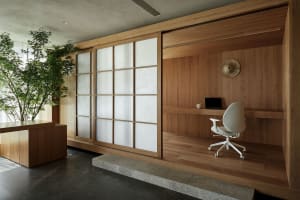 A modern home office featuring wooden walls, a white office chair, and a sliding shoji screen.
