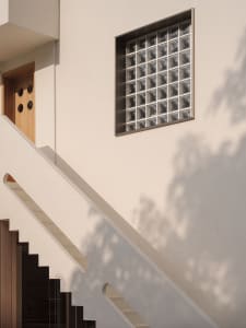 A modern staircase with a glass block window allowing natural light to illuminate the space, featuring white walls and a wood