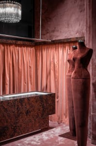 Luxurious retail store display featuring velvet curtains and mannequins.
