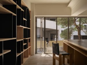 A modern library with wooden shelves and a wooden table with a black chair.