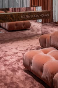 A modern living room featuring plush velvet couches with rounded contours and metallic accents.