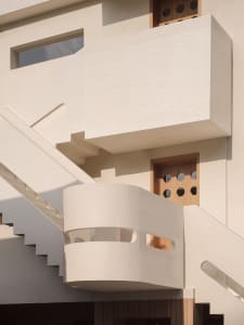 Modern concrete staircase with curved balustrades and white railings.