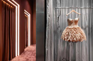 A fashion dress displayed on a hanger in a room with gray curtains and lit pathways.