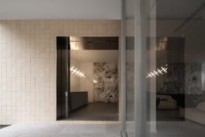 A modern industrial lobby with concrete and tile walls, featuring a minimalist design with geometric lighting fixtures.