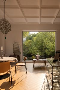 A modern lounge area with wooden flooring, glass windows, and leather furniture.