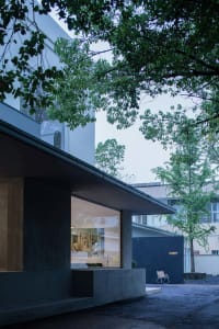 A modern outdoor space featuring a building with large glass windows and concrete walls.