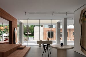 Modern living room featuring exposed concrete floor and brick wall, with minimalist furniture and large windows.